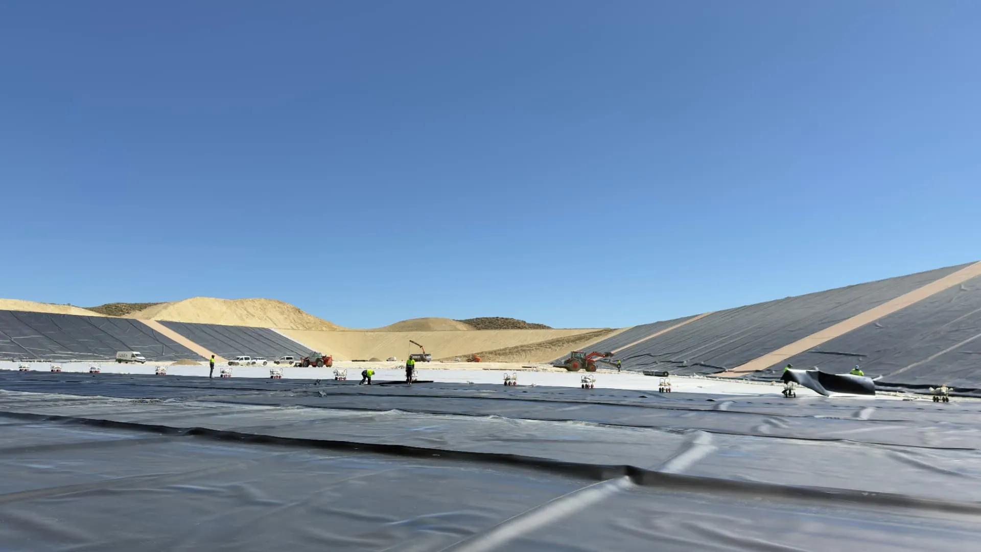 Paños de geomembrana distribuidos sobre la superficie de una gran balsa