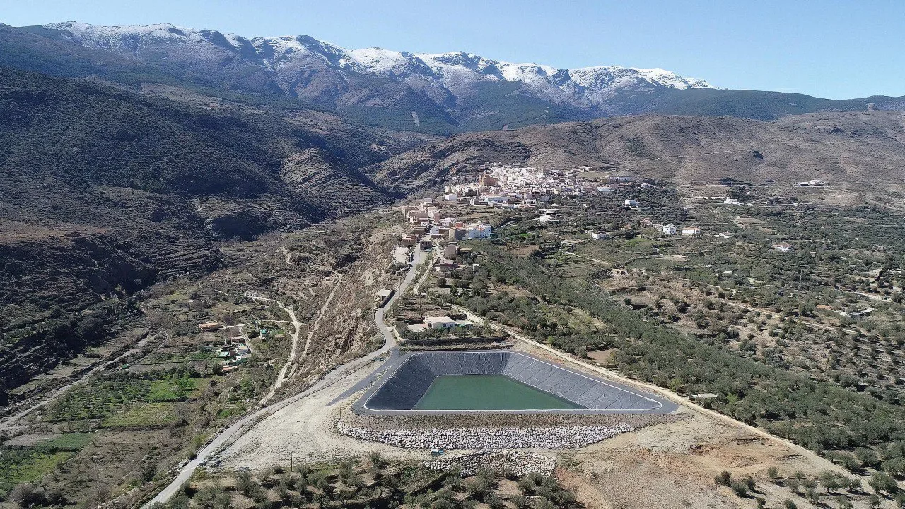 Balsa impermeabilizada con lámina negra integrada en un valle de cultivos